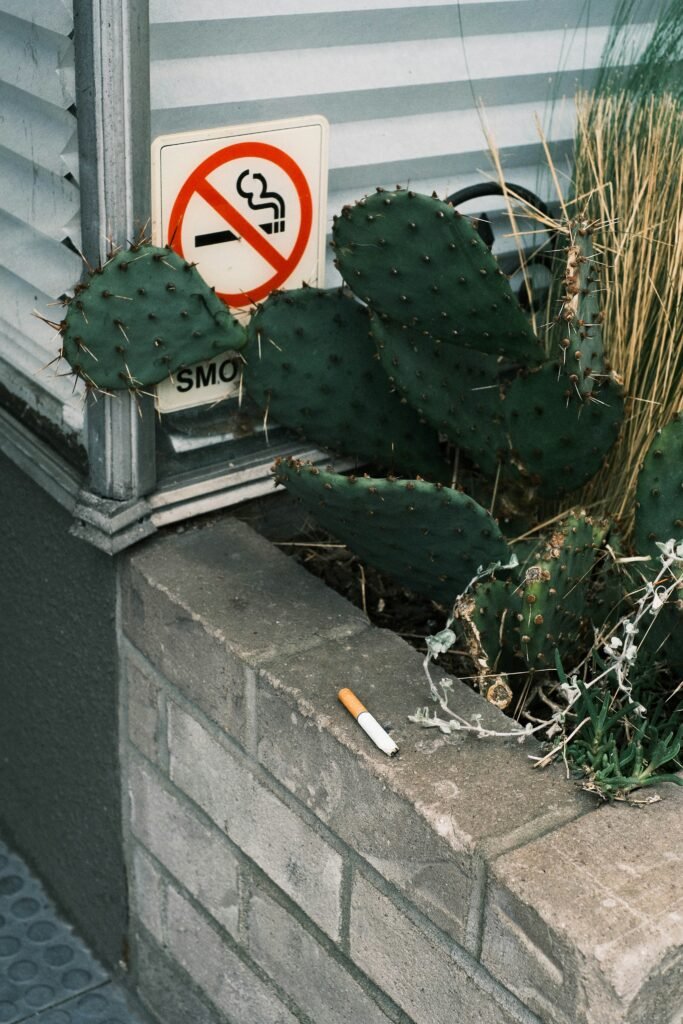 imagien d'une cigarette sur un muret avec un panneau sur le mur montrant un cigratette interdit